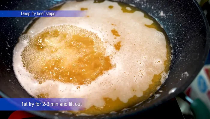 Deep fry the beef (first fry): Preheat sunflower oil in a frying pan. Fry the coated beef strips for 1-2 minutes until lightly browned. Remove from the oil.