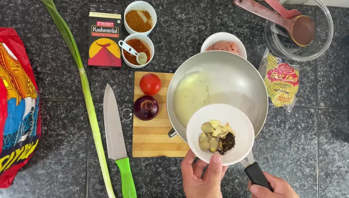 Heat oil in a pan. Add garlic, ginger, cloves, and Schezwan seeds. Fry until fragrant, then strain the oil and pour it over the chilli powder mixture. Mix well until the chilli powder is soaked in the oil.
