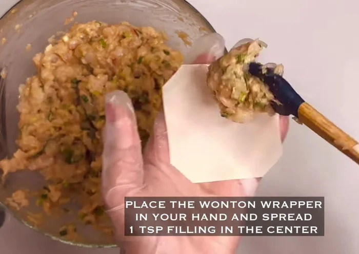 Take one dumpling wrapper, place one teaspoon of filling in the center, and use a straw to gently shape it into an open dumpling.
