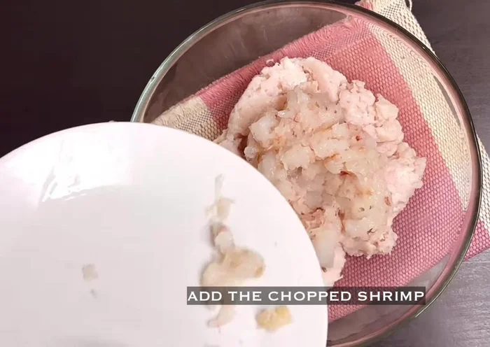 Transfer chicken meat to a bowl. Add chopped prawns, grated ginger, garlic, green onions, soy sauce, oyster sauce, sesame seed oil, sugar, white pepper, chicken powder, and cornstarch. Mix well.