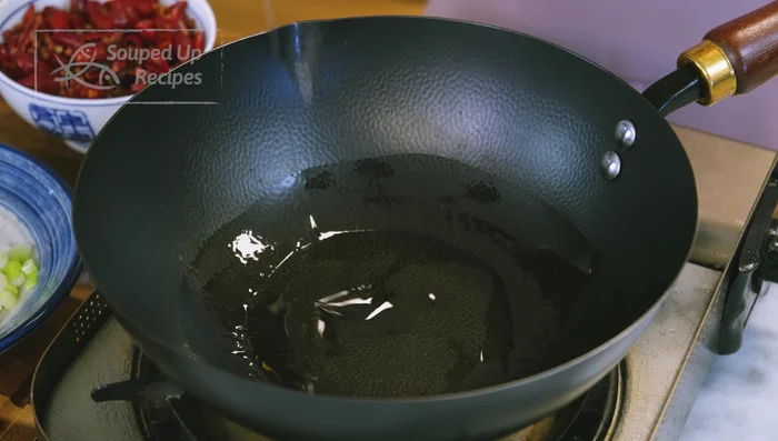 Pour out oil, clean wok, and add a drizzle of fresh oil. Stir-fry soaked chilies and Sichuan peppercorns until moisture evaporates.