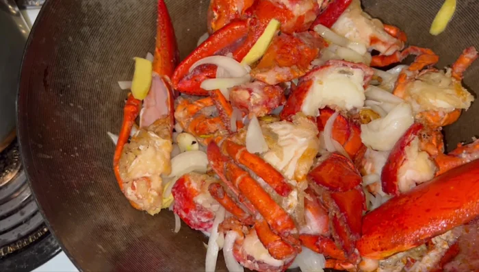 Add lobster pieces to the wok, season with salt and sugar. (971.839)