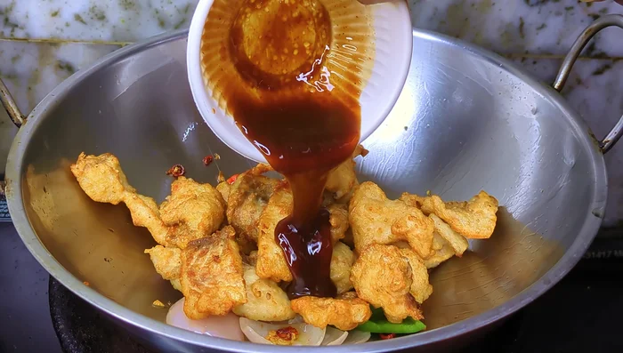 Return the fried fish to the kadai. Pour in the sauce mixture and add a splash of water. Cook for 2-3 minutes until sauce thickens.