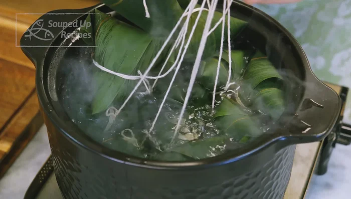 Boil zongzi in a large pot of water for 2.5 hours, using a plate to keep them submerged.