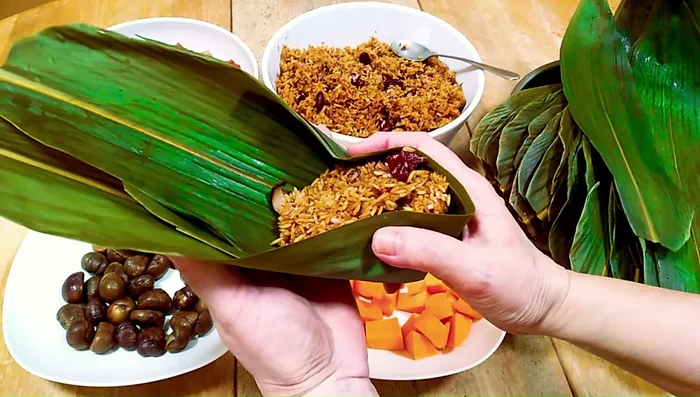 Pat down the filling, fold the top leaves over the rice, and tie with cotton string.