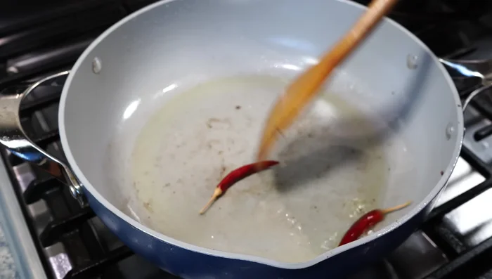 Add more oil to the pan. Fry dry red chilies briefly, remove one for garnish. Add bay leaves and the five-spice blend; fry on low heat until fragrant.