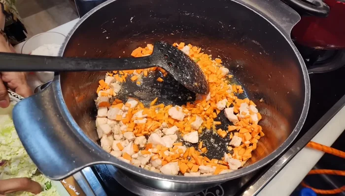 Fry the chopped chicken pieces in the leftover oil from frying the onions and capsicums. Add chopped carrots, cabbage.