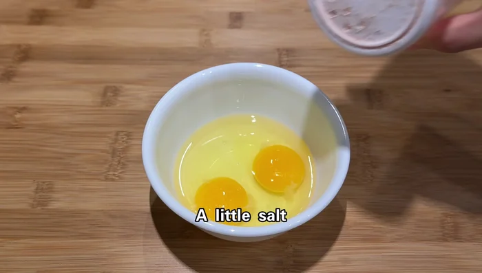 Crack eggs into a bowl, add a pinch of salt, and beat well.