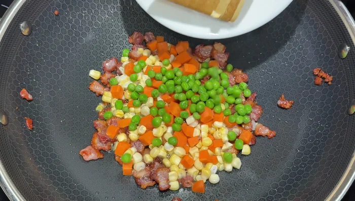 Add carrots, corn, and peas to the wok and cook for a minute or two. Then add shallots.
