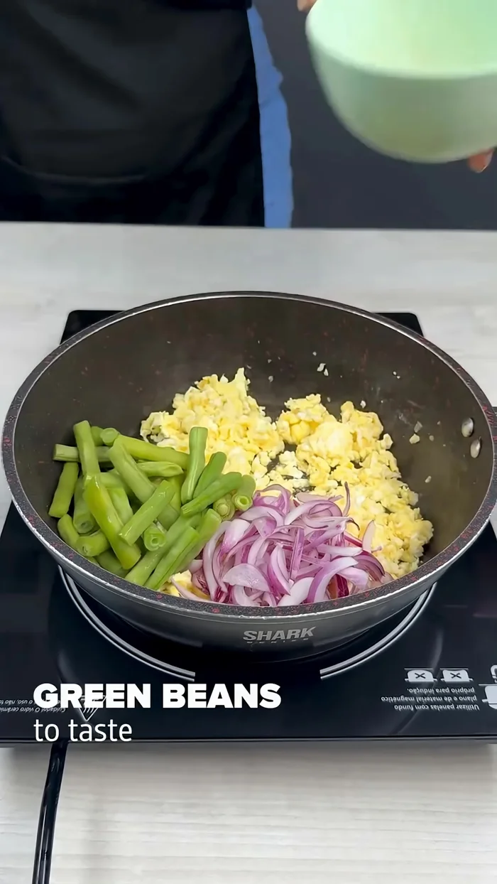 Add 1/2 sliced onion, green beans to taste, 1/2 carrot, 1/2 yellow bell pepper, 1/2 green bell pepper, 1/2 red bell pepper, and 1/2 cabbage. Mix well and fry for 5 minutes.