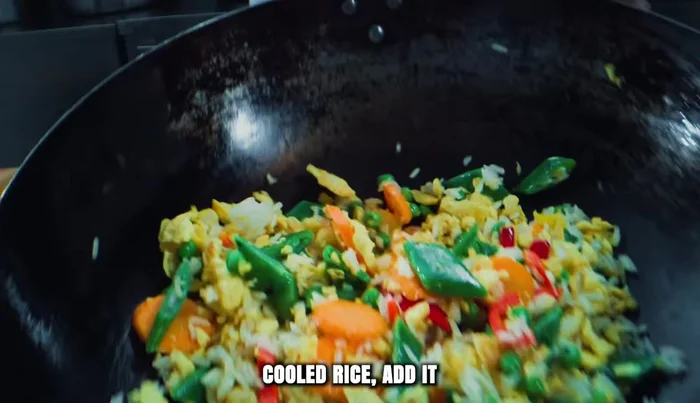 Gently add the cooled rice to the wok, breaking up any clumps with a spatula. Let it sit for a few moments to warm through.