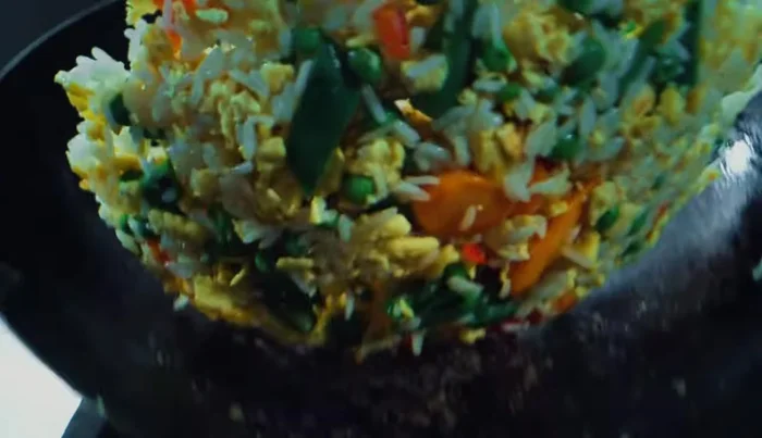 Fold the rice into the vegetables without pressing. Pour in 2 tablespoons of light soy sauce, 1 tablespoon of dark soy sauce, and 1 teaspoon of sesame oil. Season with salt and white pepper.