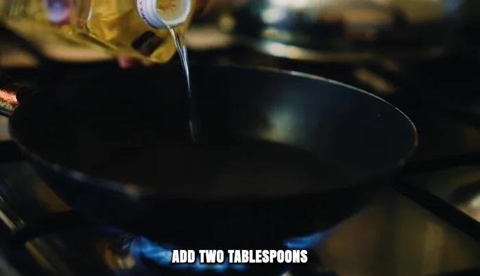 Heat a wok with 2 tablespoons of vegetable oil and 1 tablespoon of sesame oil. Add 3 cloves of finely chopped garlic and 1 inch of minced ginger. Let their fragrance rise without browning.