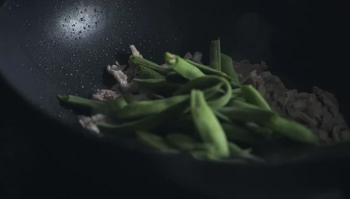 Once the pork is browned, add green beans and toss. Season lightly with salt, tasting as you go.