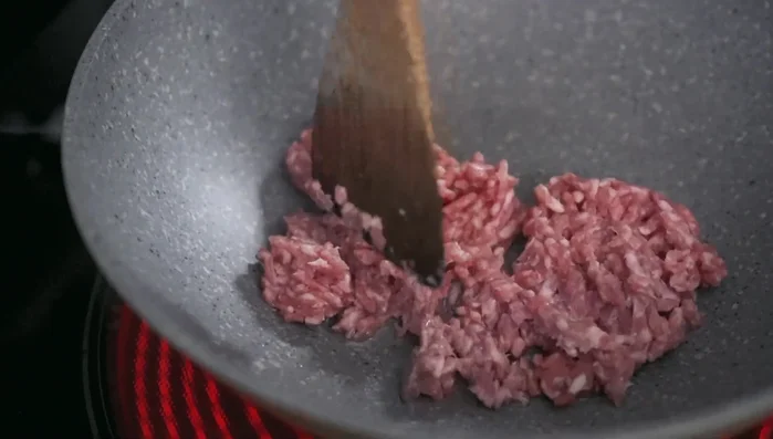 Stir-fry the pork: In a nonstick wok, stir-fry the ground pork on low heat (277.04) until cooked through. Add cooking alcohol and white pepper to remove any strong odors (291.36, 300). Increase heat and let liquid evaporate (313.12).