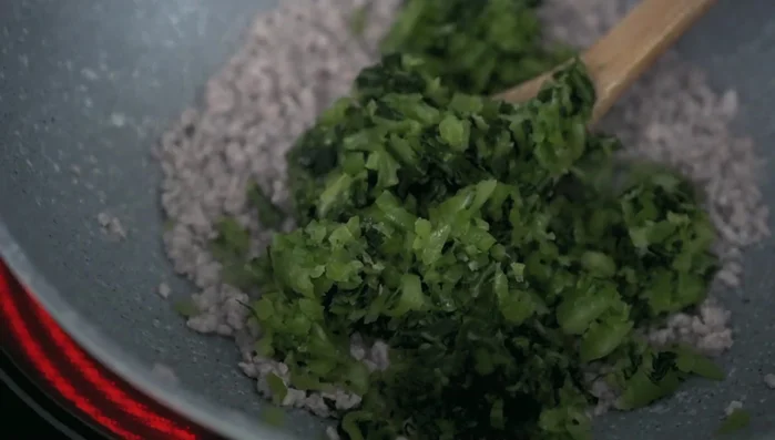 Combine and season: Add the minced mustard greens to the pork, then season with fish sauce and soy sauce (349.919). Taste and adjust seasonings as needed (359.12).