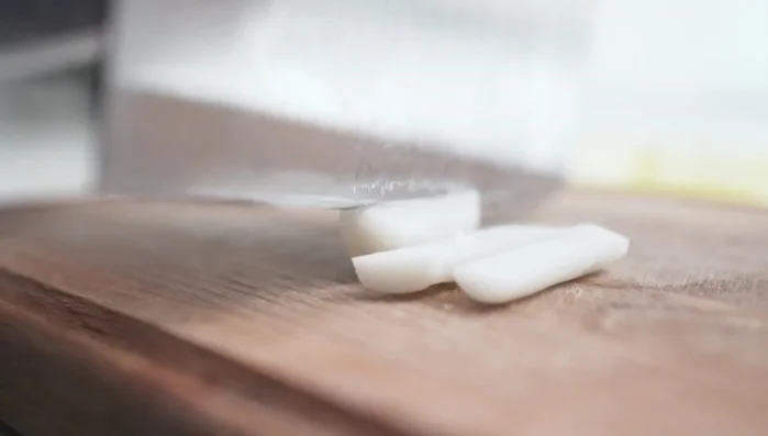 Prepare the rice cakes: Slice rice cakes in half (77.439) for softer texture and even cooking (79.6).