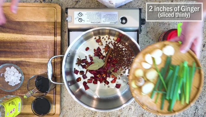 Add a few ginger slices, 5 garlic cloves, and 2 scallions. Stir in 1 tablespoon of Sichuan doubanjiang.