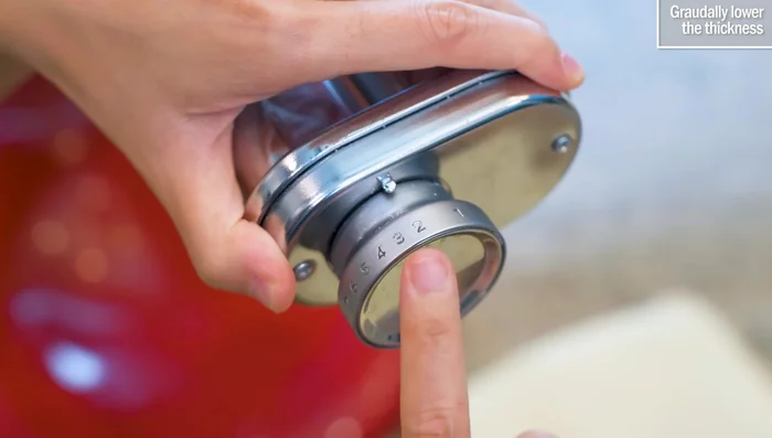 Gradually reduce the thickness setting on the pasta roller until the desired thickness is reached.