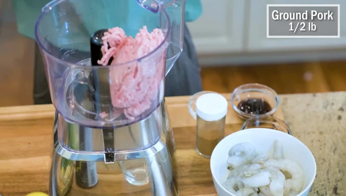 Make the wonton filling: In a food processor, combine ground pork (or chicken), shrimp, diced scallions, cilantro, minced garlic, minced ginger, soy sauce, oyster sauce, sugar, five-spice powder, sesame oil, and water. Blend for 30 seconds.