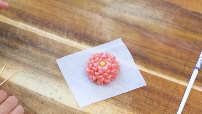 Add a small yellow ball in the center and green beads around it (218.64).