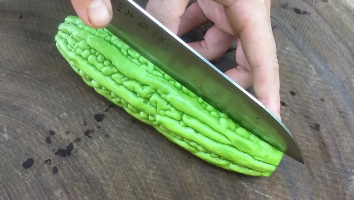 Clean the bitter melon and cut off the ends. Cut it in half and remove the inner pith, especially the white core if sensitive to bitterness.