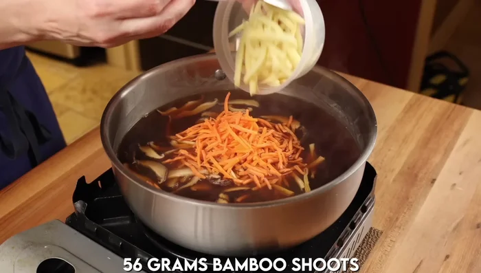 Add ingredients to broth: Add par-cooked meat, both mushrooms, lilies, carrots, bamboo shoots, and sliced tofu to the broth. Simmer for 3-5 minutes.