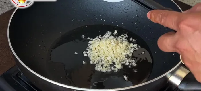 Sauté aromatics: Reduce the oil in the pan. Add thinly sliced garlic and cook for 15-20 seconds over moderate heat. Add sliced white onion and cook for about a minute until translucent.