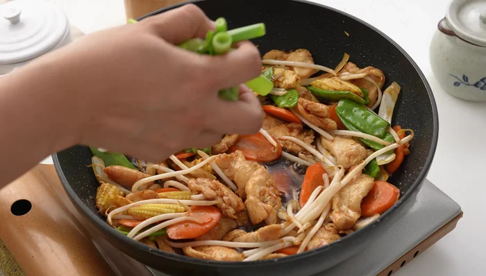 Add the cornstarch slurry and spring onions. Stir and cook for another minute until the sauce is glossy.