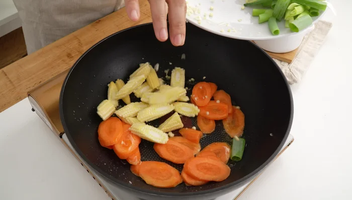 Stir-fry the carrots and baby corn for 30 seconds. Then add snow peas and onions, stir-frying for about a minute until tender-crisp. Remove and set aside.