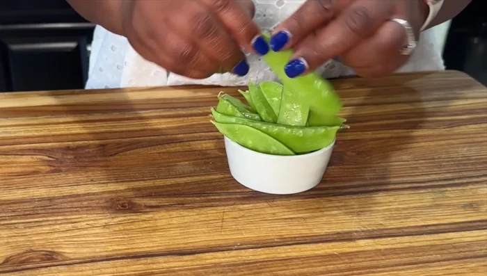 Prepare vegetables: trim snow peas, cut squash, bell pepper, onions, broccoli, and carrots.