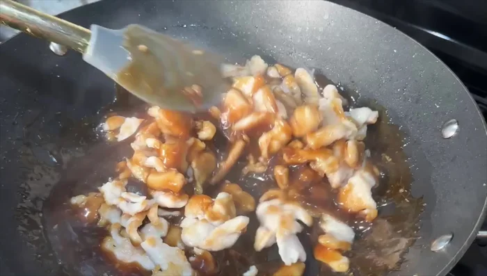 Add the cooked chicken and blanched vegetables to the wok.